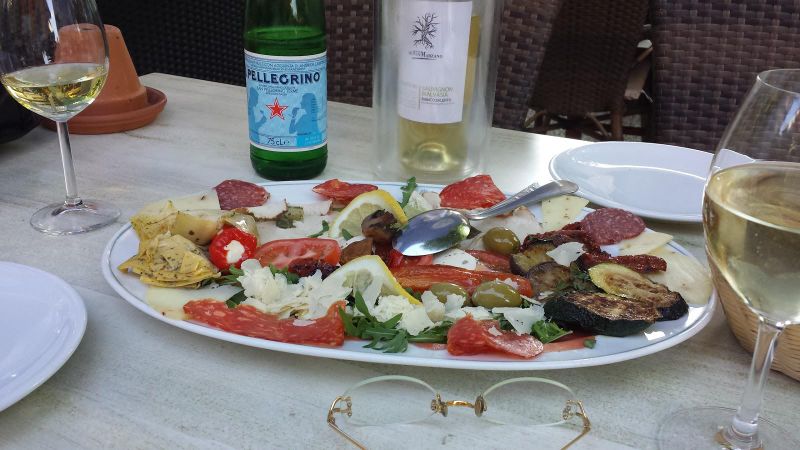 Antipasto-Platte mit Weißwein auf der Terrasse